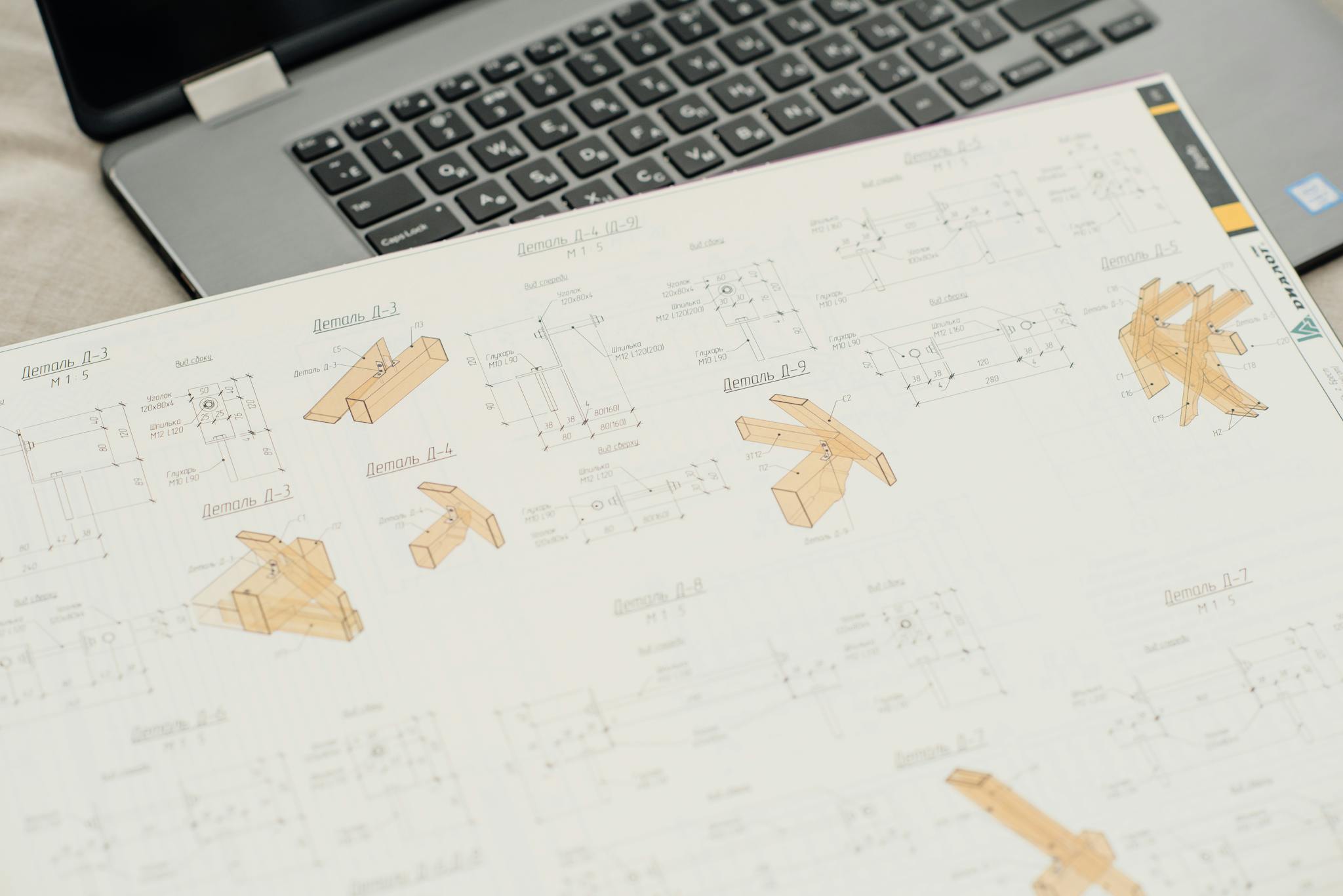 Close-up of architectural blueprints with a laptop on an office desk, showcasing design and planning.